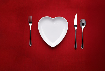 A heart shaped plate and place setting on a table.