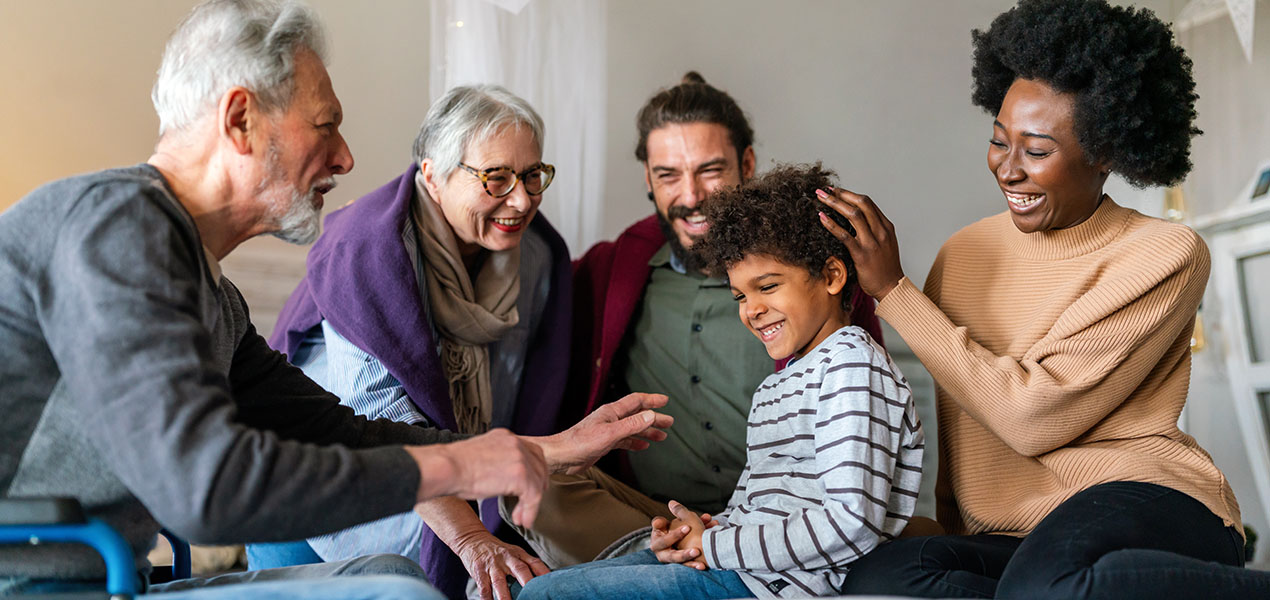 Three generations of a happy multiethnic family chatting at home.