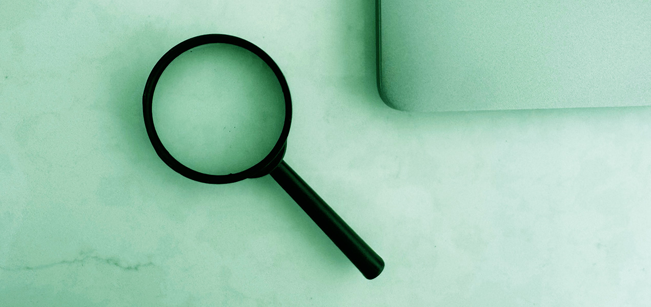 A magnifying glass and a laptop on a table.