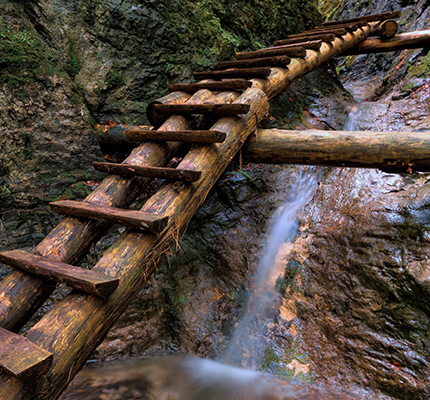 A wooden ladder rising up over a waterfall.