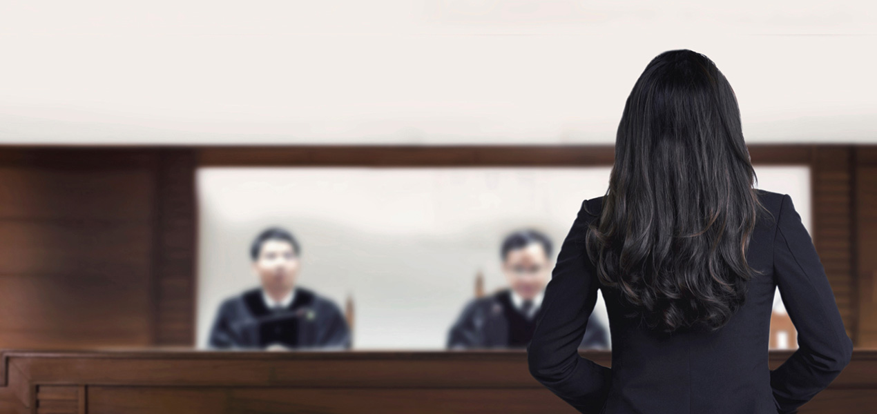 Female attorney standing and speaking in a courtroom.