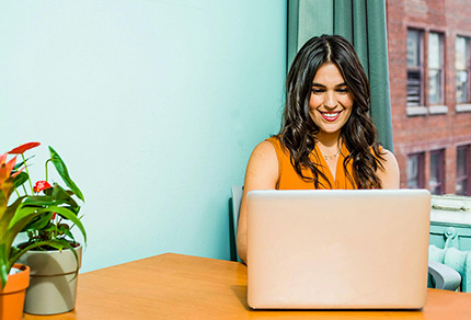 A young woman sitting at a table with her laptop.