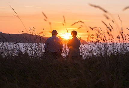 An elderly couple watching the sunset. 