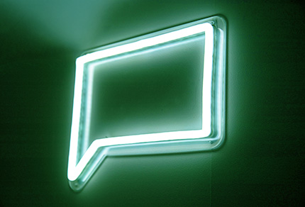 A bright neon sign of a speech bubble.