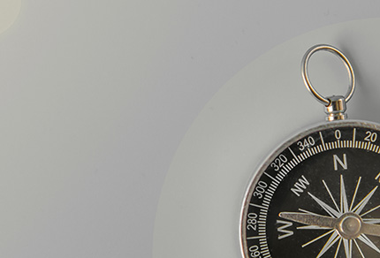 A compass sitting on a grey background.