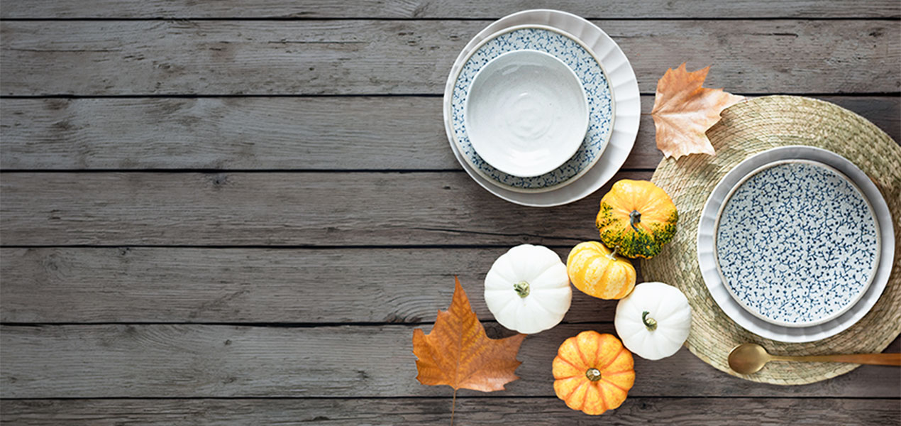 A festive autumn place setting on a rustic wood table.