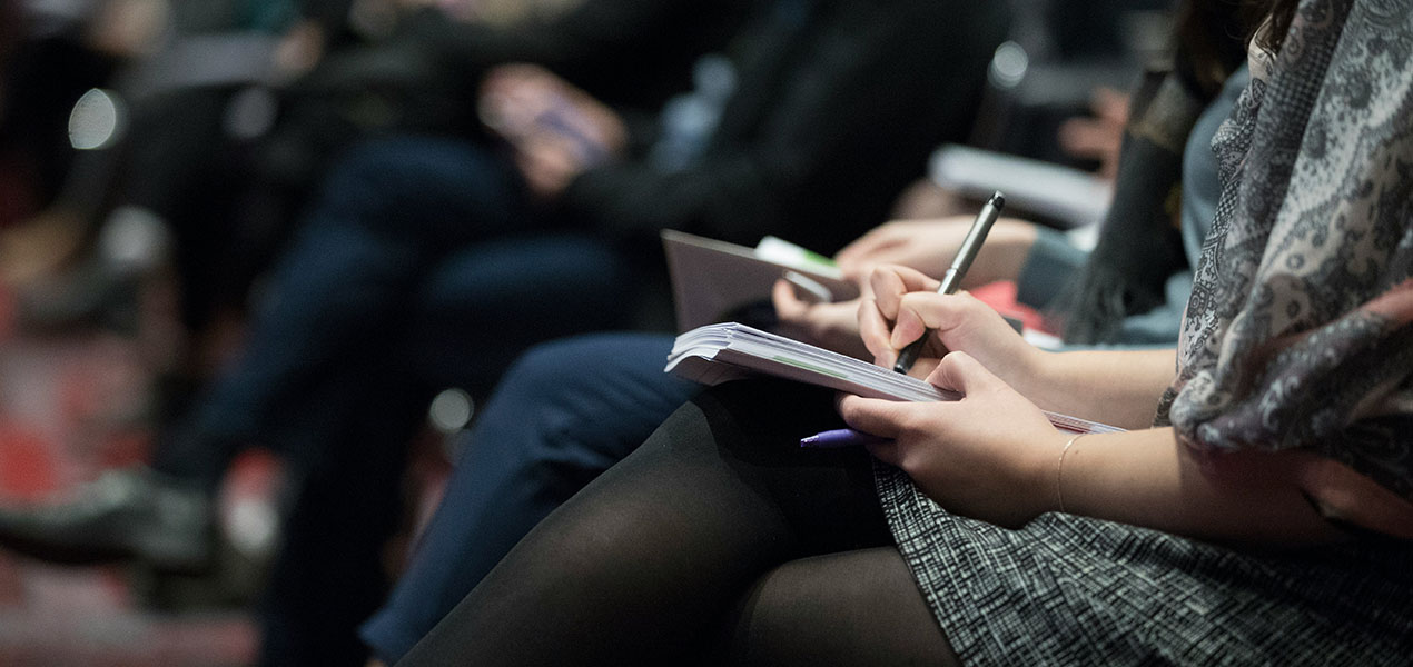 Close up of a conference attendee taking notes.