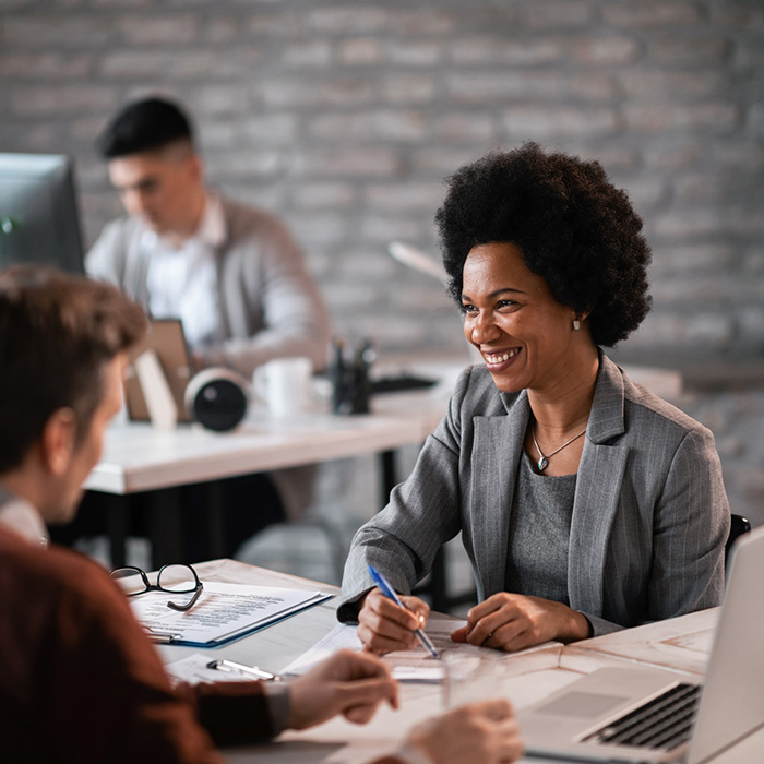 Smiling Black female business professional talking to a couple.