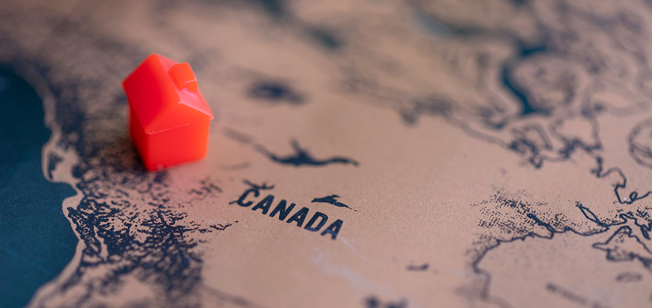 A small toy house placed on top of a map of Canada.