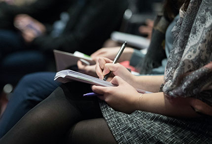 Close up of a conference attendee taking notes.