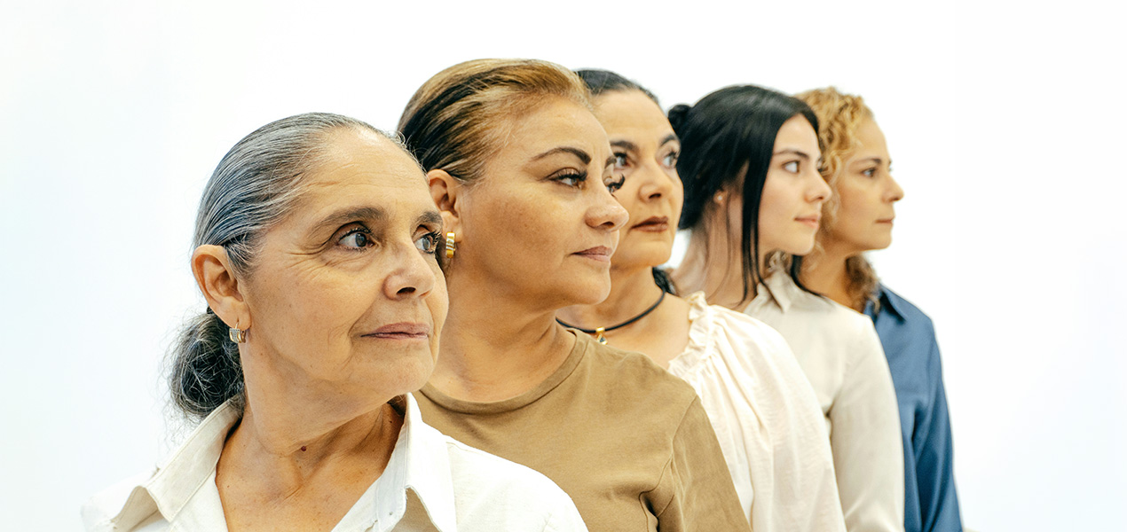 Multiple generations of women standing in a row looking off into the distance.